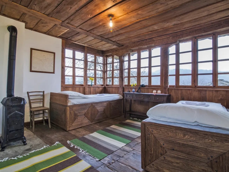 Bedroom where rustic charm meets breathtaking mountain views. This cozy wooden bedroom reflects the beauty of Central Balkan rural architecture and offers a serene environment surrounded by lush forests and majestic peaks. 